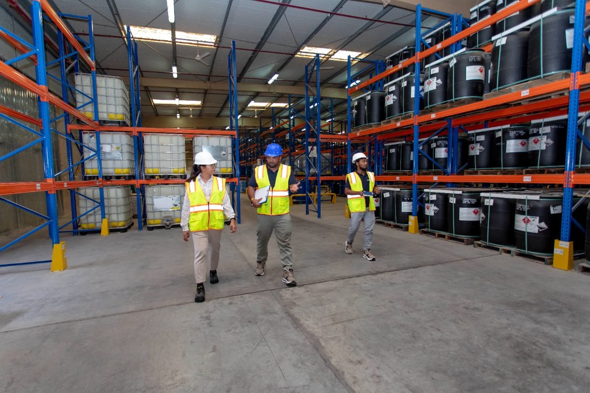 Three colleagues in PPE walking the aisle of the DG store, one talking through a clipboard